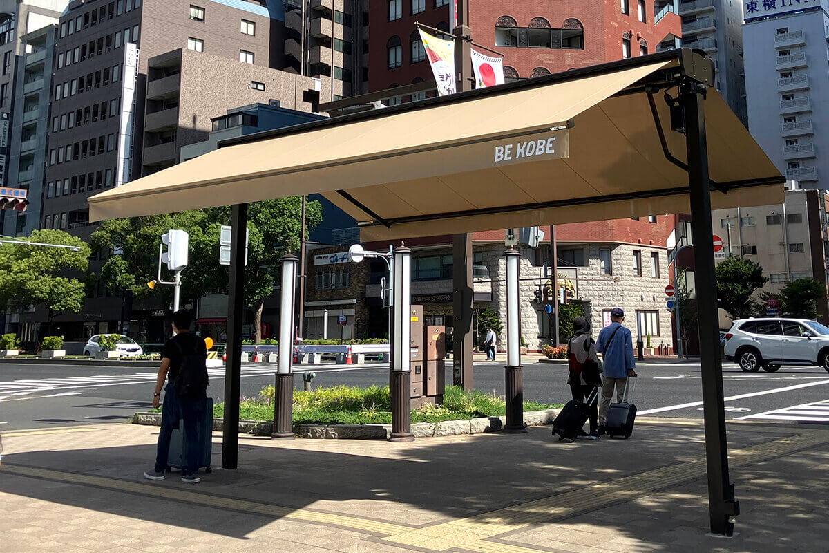 信号待ちの歩行者がスマートシェードの日陰を利用